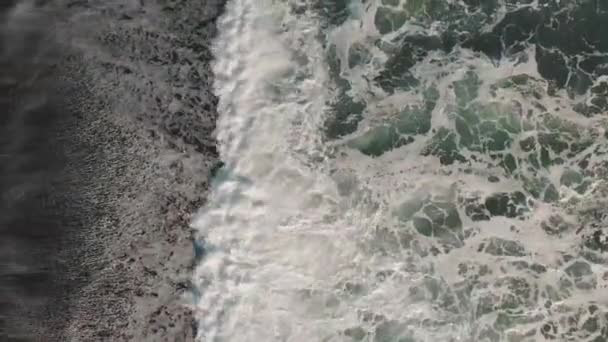Letecký pohled na divoké vlny s pěnou na břehu černé sopečné pláži na Islandu. — Stock video