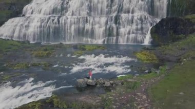 Waterfall tarafından İzlanda üzerinde yürüyen mutlu kadın. Casual giyim İzlanda doğa manzara ziyaret turist kız. Hava