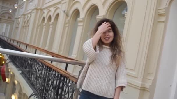 Jovem mulher andando pelo shopping sorrindo. Cliente feminino no corredor do shopping center à procura de vendas. Conceito de consumismo de compras — Vídeo de Stock