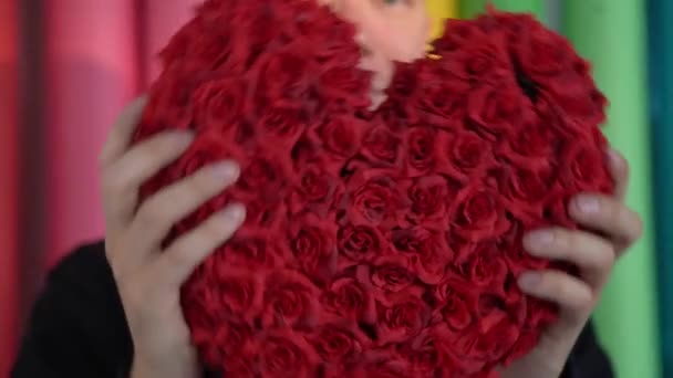 Handsome young man is showing his love with a red heart as a gift on a Valentines Day. — Stock Video