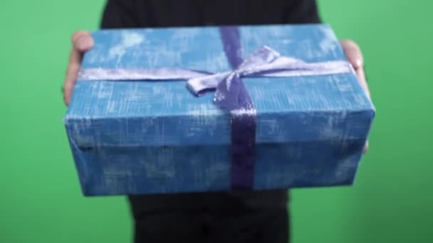 Un uomo con un regalo di Natale. Primo piano delle mani maschili che danno confezione regalo contro lo schermo verde . — Video Stock