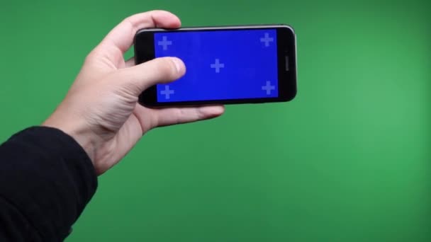 Elinde telefon yakın çekim yeşil arka plan izole. Telefon ekran mavi chroma anahtar, arka plan chroma anahtar yeşil ekran var. Mobil reklamlar, app promo dikey smartphone ekran görüntüleri. — Stok video