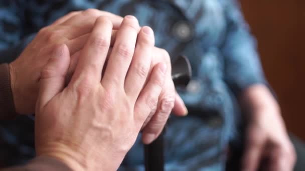 La mano de un joven coge la mano de un anciano, signo de amor, ayuda, fe y apoyo, ayuda a los familiares. Concepto pensión, sanatorio, asilo de ancianos, ayuda para los ancianos — Vídeo de stock