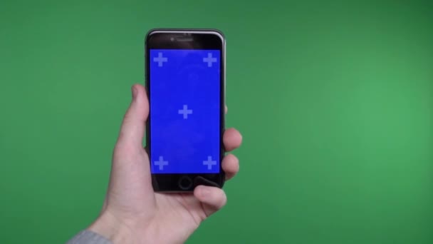 Phone in the hand close up isolated at green background. Phone screen is blue chroma key, background chroma key green screen. Footage for mobile ads, app promo vertical smartphone screen. — Stock Video