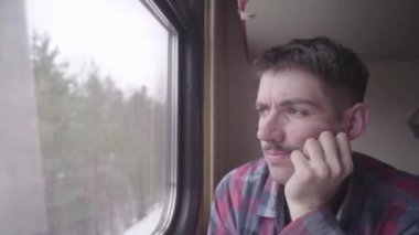 Tren ile seyahat ve hareket ederken dışında pencereden dışarı bakarak genç adam yolcu