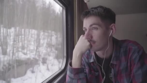 Passageiro jovem viajando de trem e olhando para fora da janela, enquanto se move — Vídeo de Stock