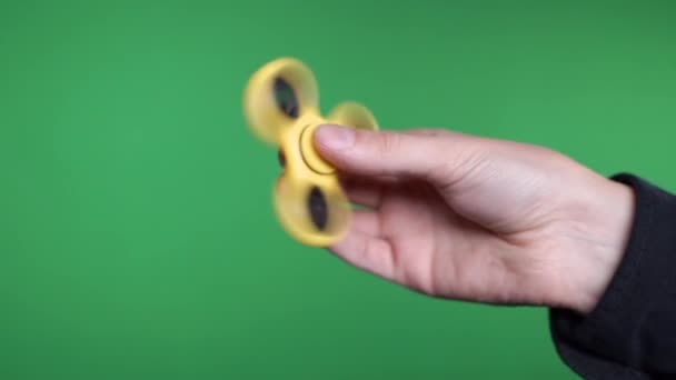 Gul Spinner snurrar på en grön skärm för hand — Stockvideo