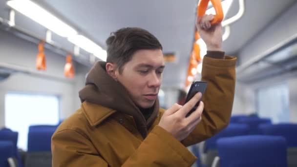 Zamknąć widok przystojny mężczyzna stojący na Transport publiczny. Wnętrze w zatłoczonym tramwaju. Typy człowieka na jego telefon komórkowy. Luksusowy zegarek na rękę. Dorywczo Odzież. — Wideo stockowe