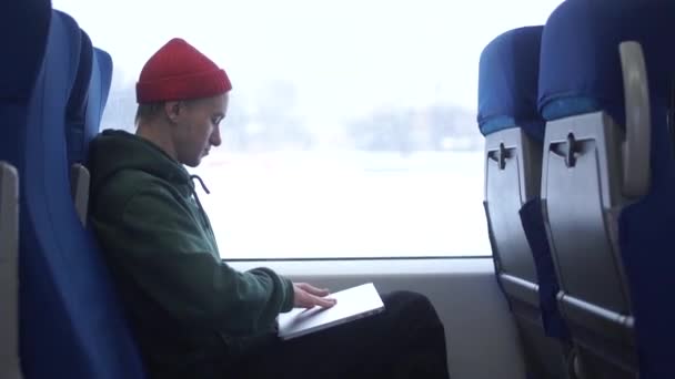 Beau jeune homme d'affaires dans une chemise et un jean parle au téléphone et en utilisant son ordinateur portable tout en conduisant un train . — Video