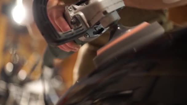 用砂纸抛光金属油箱的人 汽车修理工在他的车间里组装定制摩托车 盖伊在车库里创造了一个独家的摩托车赛车手 — 图库视频影像