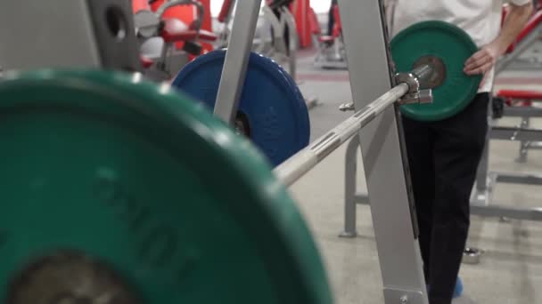 Gros plan macro gros plan de beau bodybuilder gars se préparer à faire des exercices avec haltère dans une salle de gym, garder la plaque haltère dans les mains, homme de sport . — Video