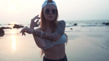 Güzel seksi kız sahilde bir mayo ile tatto günbatımında dans