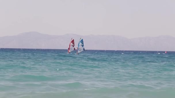 Grecce. Rhodos. 2018 Windsurfer atrapa rápidamente el viento y aumenta la velocidad en aguas de la bahía de Galway. Con otros windsurfistas — Vídeos de Stock