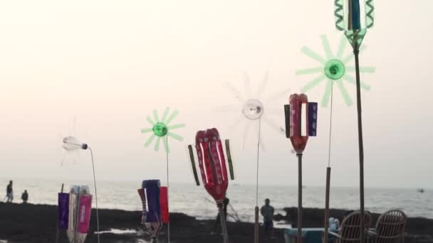 Un mulino a vento di plastica colorato con vento che soffia si trova nella sabbia in riva al mare sullo sfondo della spiaggia. Giocattolo sulla spiaggia del mare — Video Stock