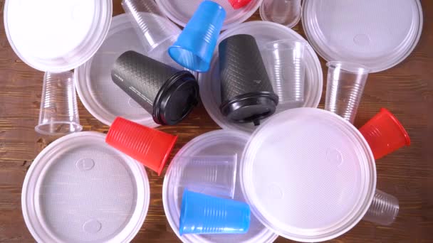 Menselijke hand vegen weg plastic gebruiksvoorwerpen wegwerp gerechten, kleurrijke borden, kopjes, drinken rietjes, bestek en katoen Bud stokken. Schone achtergrond voor de geschreven — Stockvideo