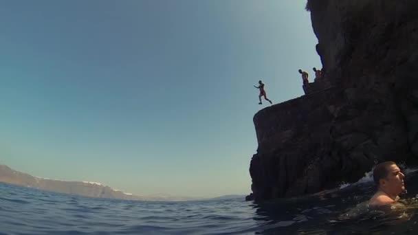 Santorini. Grecia.2018 Hombre saltando desde el acantilado hacia el océano. Estilo de vida divertido verano . — Vídeos de Stock