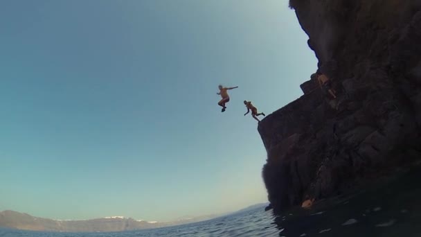 Santorini. Grecja. 2018 człowiek skaczący z urwiska do oceanu. Letni zabawny styl życia. — Wideo stockowe