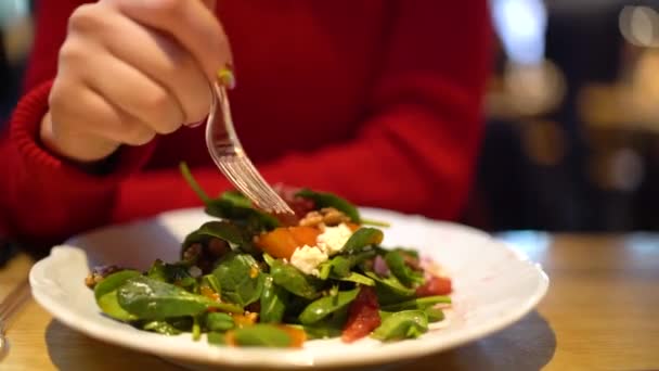 Женщина ест здоровый салат, сидя на столе. Закрыть — стоковое видео
