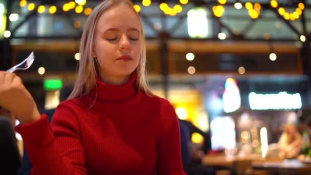 Mujer joven y feliz comiendo ensalada saludable sentada en la mesa — Vídeos de Stock