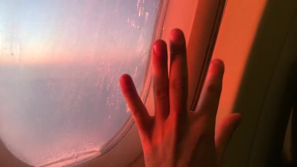Mans hand silhouetted to the porthole in a plane of economy class on sunset. hello travel — Stock Video