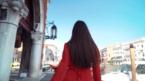 Young girl in a red drees walks along the street and turns around. Venice, Italy. — Stockvideo