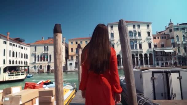 Chica joven en una drees rojo camina por la calle y se da la vuelta. Venecia, Italia . — Vídeos de Stock