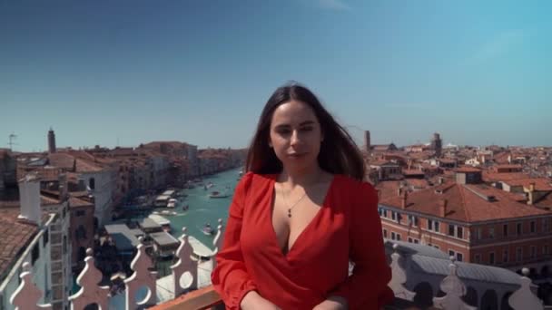 Junge schöne brünette Frau in einem roten Kleid vor blauem Himmel und Fluss, Dach Venedig, Italien — Stockvideo