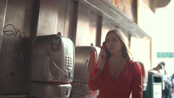 Mulher bonita falando em um telefone público. Expressão feliz . — Vídeo de Stock