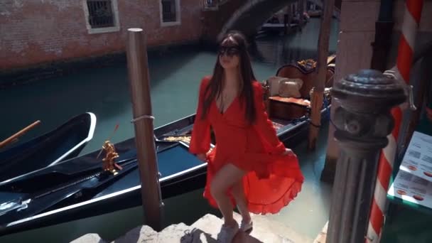 Portrait of a woman with a mysterious look at sunset in Venice. Girl wearing a black mask and a gondola on the Canal background, Italy — Stock Video