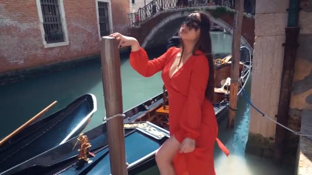 Porträt einer Frau mit geheimnisvollem Blick auf den Sonnenuntergang in Venedig. Mädchen mit schwarzer Maske und Gondel auf dem Hintergrund des Kanals, Italien — Stockvideo