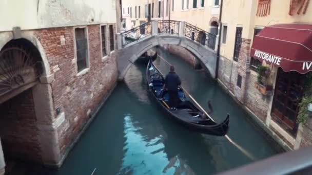 VENECIA, ITALIA, abril 2019: Góndolas con turistas nadan a lo largo de un estrecho canal en Venice Street, Italia. Canal de agua de Venecia. Edificios de arquitectura . — Vídeos de Stock