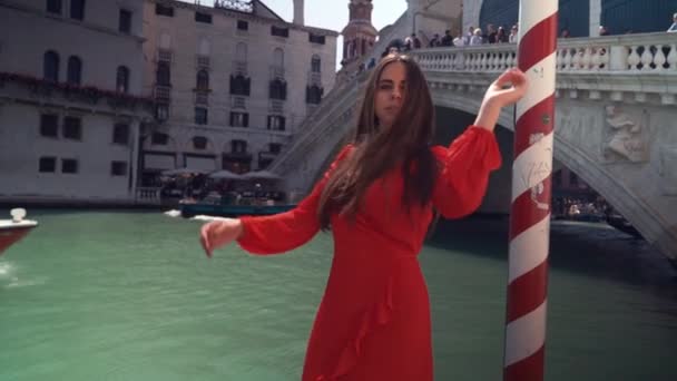 大運河の近くに赤いドレスを着た幸せなセクシーな女性。ヴェネツィアで休暇を楽しむ若い魅力的な女性. — ストック動画