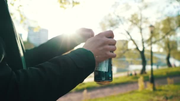 Мальчик-подросток открывает бутылку пива на закате — стоковое видео