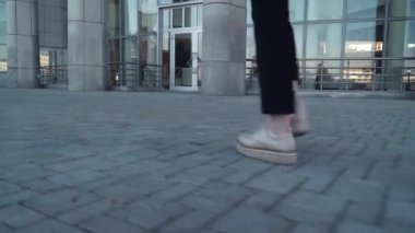elinde kağıt belge ile sokakta yürüyen siyah ceketli genç iş kadınları, bacaklar kadar yakın ve kağıt ile hends