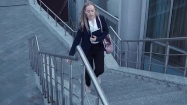 siyah ceketli genç iş kadınları geç ve elinde dizüstü bilgisayar ile merdiven üzerinde çalıştırmak