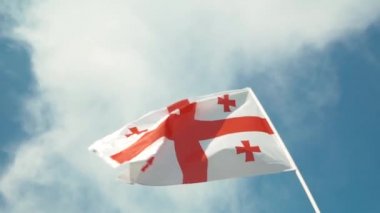 Rüzgara karşı açık mavi gökyüzü güneşli bir günde sallayarak Georgia ülke bayrağı.