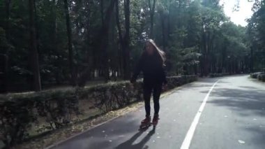 Beyaz handsom kahverengi saç kız sıkı siyah pantolon kadın Binicilik paten parkta, yaz gününde