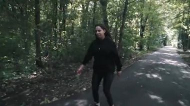 Beyaz handsom kahverengi saç kız sıkı siyah pantolon kadın Binicilik paten parkta, yaz gününde