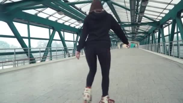 Lány vezetési görkorcsolya. Fiatal barna nő lovaglás inline korcsolyázva az utcán belvárosában, egy gyönyörű alagútban — Stock videók