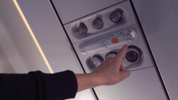 De hand van de passagier schakelt het licht in op het vliegtuig. Close-up. — Stockvideo