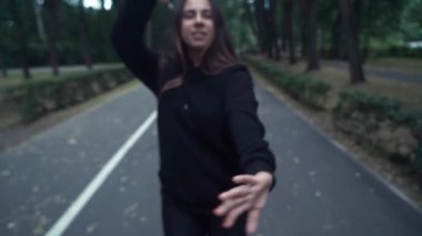 Çekici güzel genç kadın paten ve sokaklarda dans sürme. Park arka planı