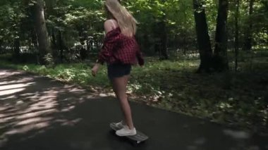 Genç kız bir yaz park Caddesi üzerinde bir kaykay sürmek