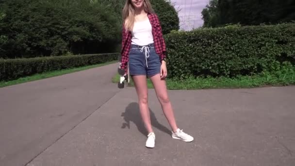 Sport och mode ung kvinna poserar vid solnedgången med en skateboard — Stockvideo
