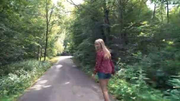 Chica joven monta un monopatín en la calle en un parque de verano — Vídeo de stock