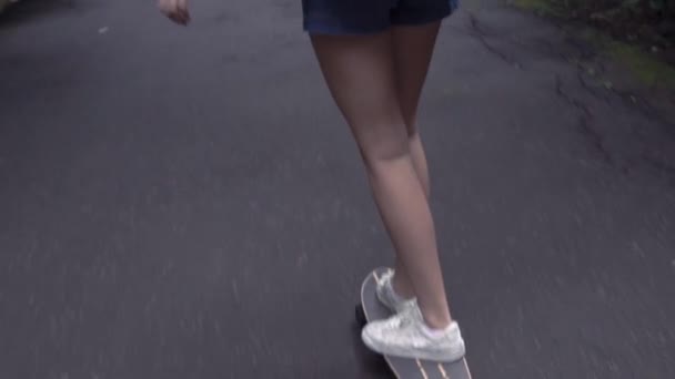 Νεαρό κορίτσι βόλτες με ένα σκέιτμπορντ στο δρόμο σε ένα καλοκαιρινό πάρκο σε αργή κίνηση — Αρχείο Βίντεο