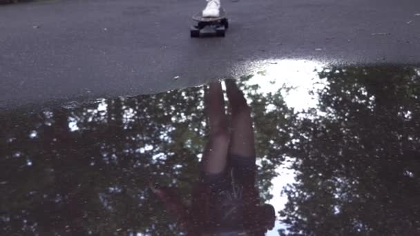 Girl riding skateboard through a puddle in slow motion — Stock Video