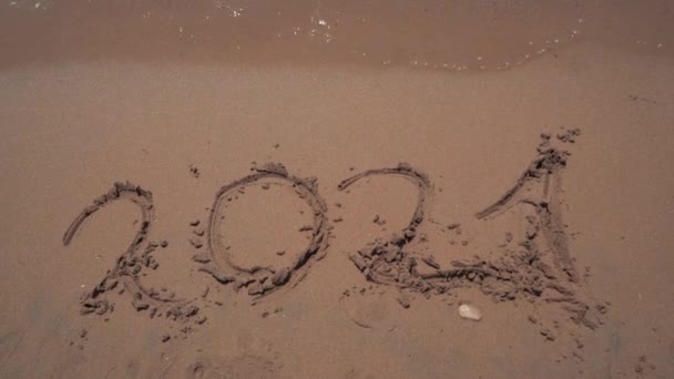 L'inscription "2021" sur le sable est emportée par la mer. chiffres sur le sable sur la plage de la mer. Bonne année 2022 vient Nouvel An 2022, remplaçant l'année 2020. Concept - nouvelle année — Video