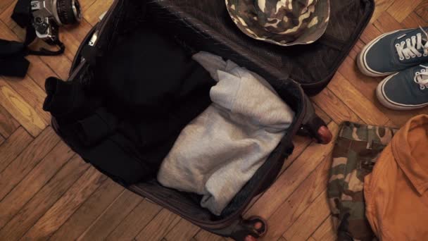 Мужские руки быстро упаковывают чемодан для путешествия. Человек мечтает о путешествии. Летняя одежда, паспорт с деньгами и водолазная маска с трубкой. Вид сверху — стоковое видео