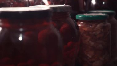 Yaşlı kadın eli shel bir komposto bir toka alır. Konserve kompostolar bodrumda. Cam kavanozlarda tasarruf. Kışın organik içeceklere hazırlık