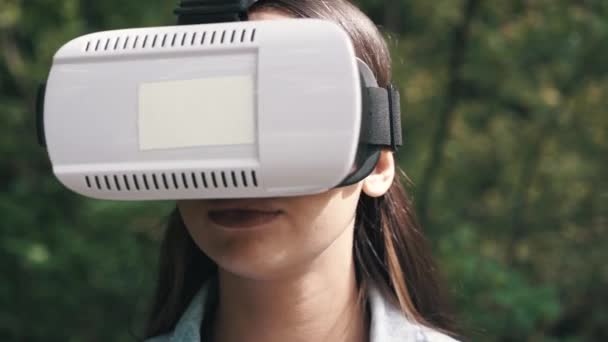 Young woman wearing vr glasses, headset, playing virtual games and watching videos outdoors in the city street. Close up — Stock Video